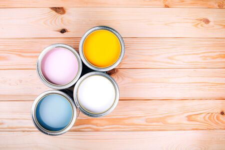 Four open cans of paint on wooden natural background. Yellow, white, pink, turquoise colors. Top view.の写真素材