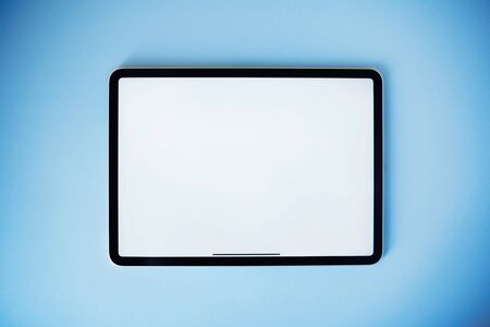 Digital tablet on blue background. Flat lay style. Clean white screen for your textの写真素材