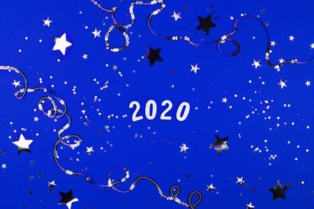 2020 on silver sparkles and blue background. Flat lay style.の写真素材