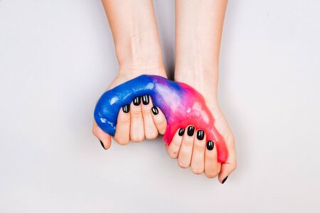 hands with black manicure holding slime in blue and pink vibrant colorsの写真素材