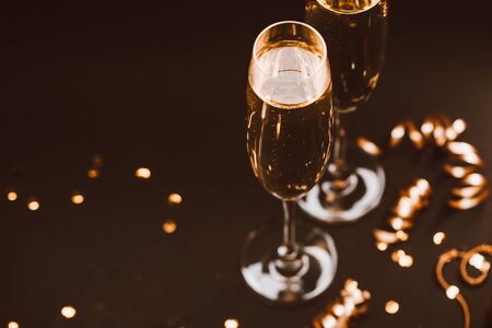 Two glasses of champagne with golden decoration on black elegant background. Top view, place for text. Festive concept.の写真素材
