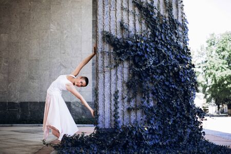 Authentic girl dances over blue plant in the city. Girl is short-haired.の写真素材