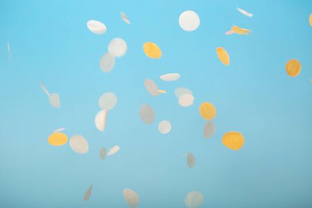 Orange and yellow falling confetti on blue backgroundの写真素材