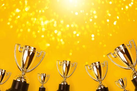 Champion cups on yellow background with sparkling lite. Tha winner takes it all!の写真素材