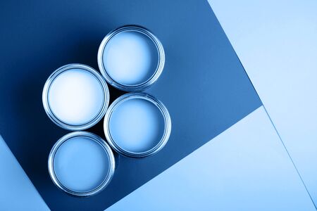 Four open cans on bright background. Yellow, white, pink, turquoise colors of paint. Top view. Renovation concept.の写真素材
