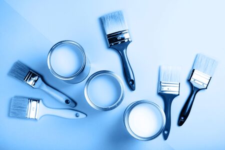 Four open cans of paint with brushes on blue background. Main color of the year 2020 in interiorの写真素材