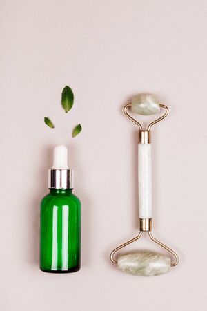 Face roller and serum on grey background. Flat lay style. Modern selfcare concept.の写真素材