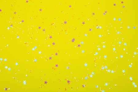 Holographic stars and silver sparkles on bright yellow background. Festive backdrop for your projects.の写真素材