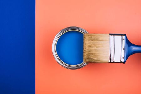 Brush on open can of blue paint on coral and blue background. Concept of changing color of the year.の写真素材