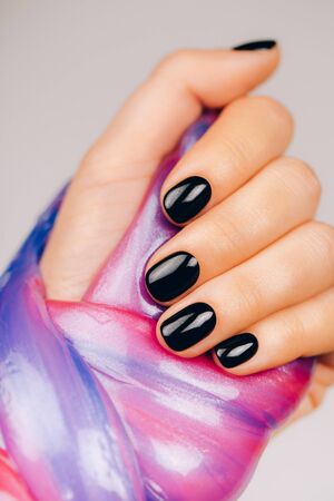 hands with black manicure holding slime in blue and pink vibrant colorsの写真素材