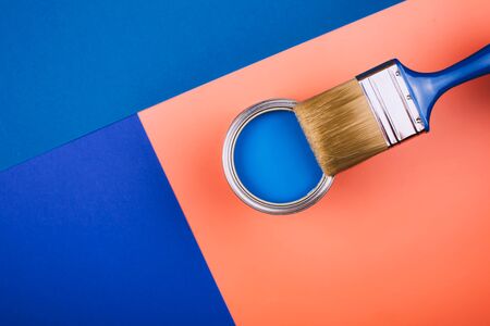 Brush on open can of blue paint on coral and blue background. Concept of changing color of the year.の写真素材