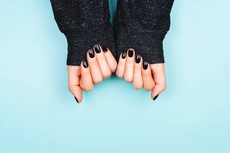 Hands with black manicure in long sleeve. Cozy lifestyle. Flat lay style.の写真素材