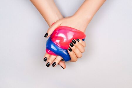 hands with black manicure holding slime in blue and pink vibrant colorsの写真素材