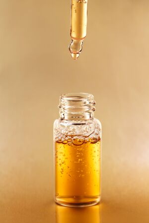 Bottle of cosmetic oil with pipette on golden background. Front view.の写真素材