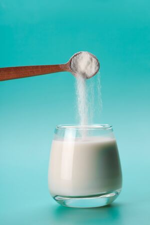 Coconut or almond milk with collagen sponon blue background with palm leafの写真素材