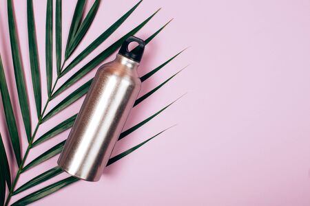 Zero waste bottle on palm leaf and pastel pink background