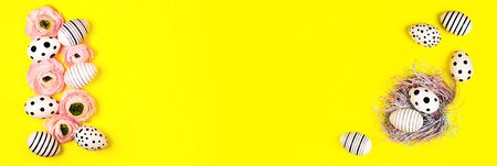 Banner with hand-painted eggs, nest and ranunculus flowers on bright yellow background. Easter...