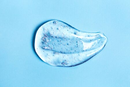 Smear of transparent gel on blue background. Virus protection or cosmetics concept.
