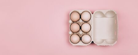 Banner made with Organic eggs in carton tray on pastel pink backgroud. Zero Waste concept. Flat lay style.の写真素材