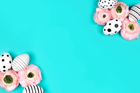 Frame of graphic hand-painted eggs and ranunculus flowers on blue pastel background. Easter concept.の写真素材