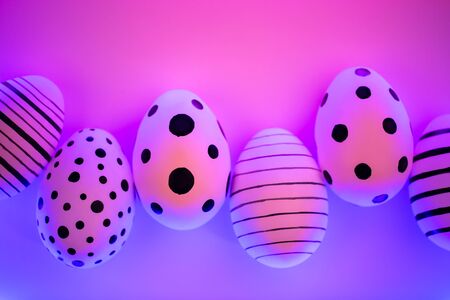 Different graphic hand-painted eggs in Proton Purple neon light. Easter concept. Top view.の写真素材