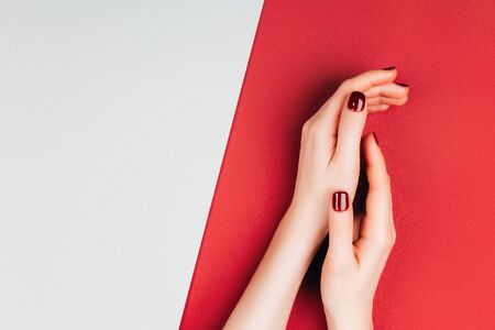 Red beautiful manicure on red and grey stylish background with copyspace. Flat lay style.の写真素材