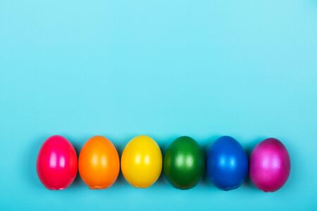 Different colorful eggs in neon trendy colors on blue pastel background. Easter concept. Flat lay style.の写真素材