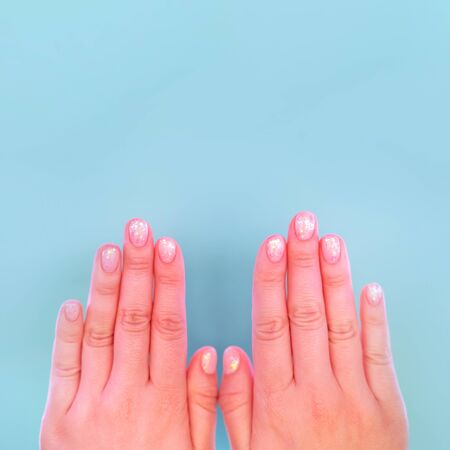 Female hands with perfect manicure in trendy neon light on pink background. Beauty concept.の写真素材