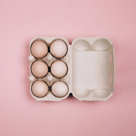 Organic eggs in carton tray on pastel pink backgroud. Zero Waste concept. Flat lay style.の写真素材