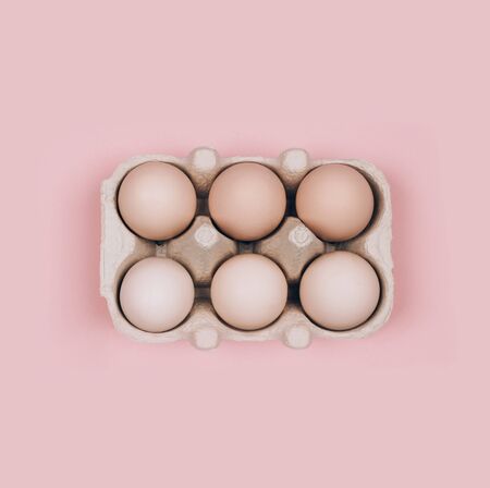 Organic eggs in carton tray on pastel pink backgroud. Zero Waste concept. Flat lay style.の写真素材