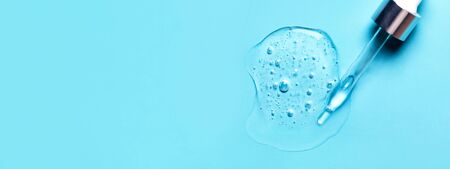 Pipette with dose of fluid hyaluronic acid on blue background. Cosmetics concept. Flat lay. Place for text.の写真素材