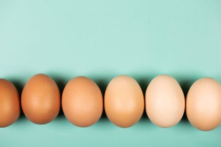 Organic chicken Eggs in line with copy space, close up on mint background. Flat lay style.の写真素材