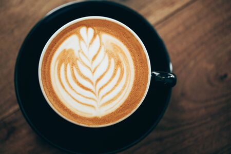 Red cup of cappucino with beautiful latte art on old wooden background. Top View.の写真素材