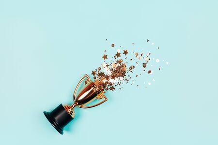 One winners cup with golden sparkles on a pastel background. Banner with copy space. Flat lay style.の写真素材