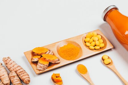 Turmeric in different conditions: fresh in bottle, pills, powder and cut plant on wooden tray. Flat lay style.の写真素材