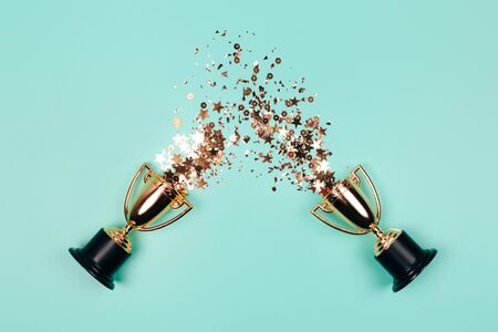 Winner cups with golden sparkles on a pastel background. Flat lay style.の写真素材