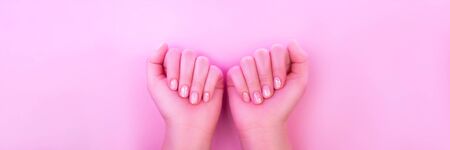 Female hands with perfect manicure in trendy neon light on pink background. Beauty concept.の写真素材