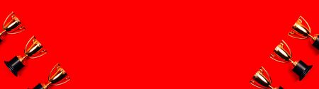 Winner cups on a red background with copy space. Flat lay style.