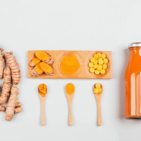 Turmeric in different conditions: fresh in bottle, pills, powder and cut plant on wooden tray. Flat lay style.の写真素材