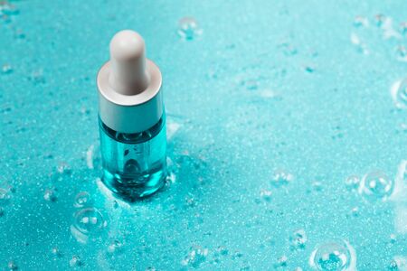 Bottle of hyaluronic acid on background with oxygen bubbles on blue background.