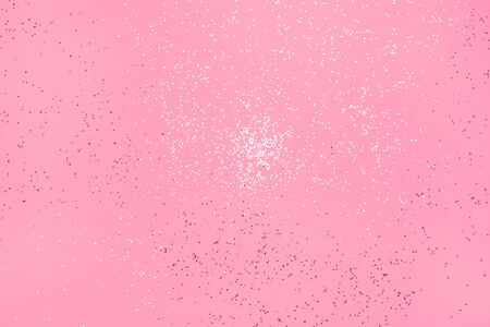 Falling silver glitter on pastel pink background. Festive concept.の写真素材