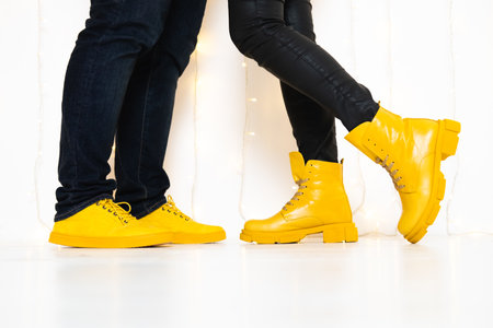 Demonstrating trendy colors of year 2021 - Gray and Yellow. Closeup unrecognizable people in stylish yellow boots walking against wallの写真素材