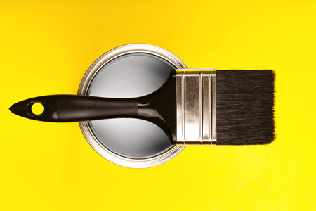Demonstrating colors of year 2021 - Gray and Yellow. Brush with wooden handle on open can. Renovation concept.の写真素材