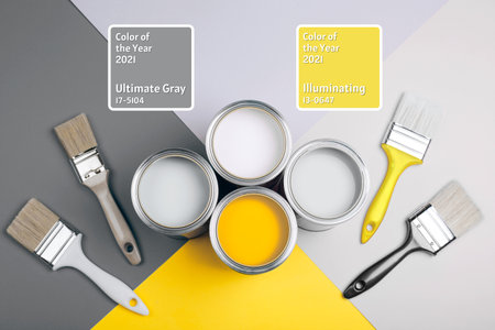 Demonstrating colors of year 2021 - Gray and Yellow. Four open cans of paint with brushes on bright background.の写真素材