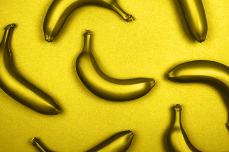 Yellow metallic bananas on monochrome background. Flat lay style. Trendy photo ispired by color of the year 2021の写真素材