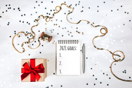 Holiday decorations and notebook with new year resolutions list on white rustic table, flat lay style. Planning concept for 2021の写真素材
