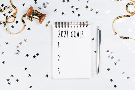 Holiday decorations and notebook with new year resolutions list on white rustic table, flat lay style. Planning concept for 2021の写真素材