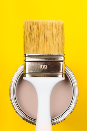 Paintbrush with beige paint on yellow background, showcasing color trendsの写真素材