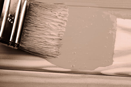 Close-up of paintbrush applying neutral paint on wooden surfaceの写真素材