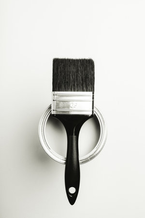 Paintbrush resting on open paint can in black and white.